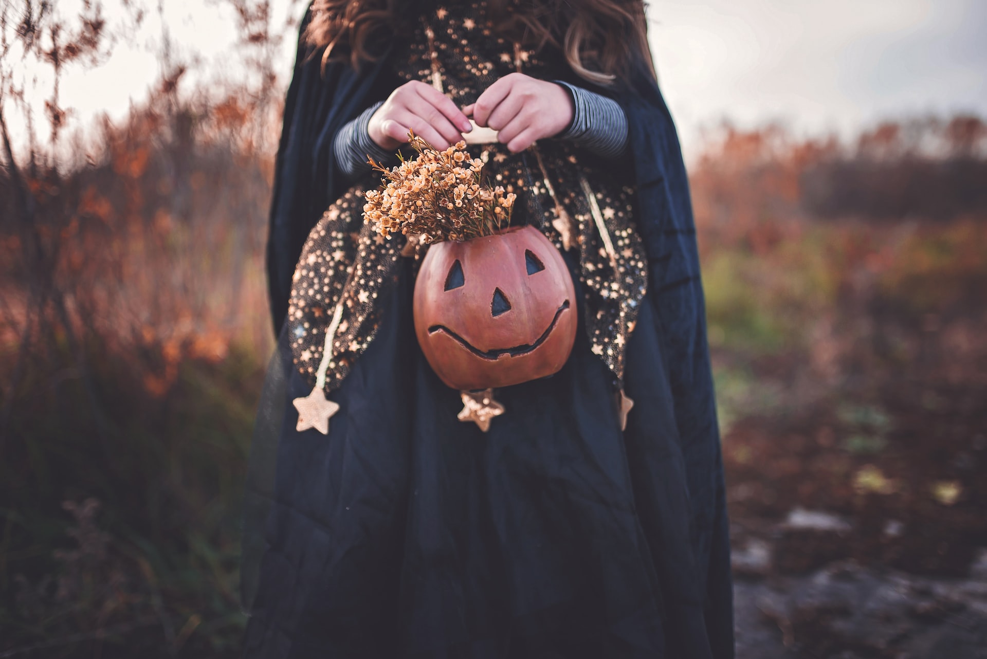 Witch holding a pumkin full of autumnal leaves and plants