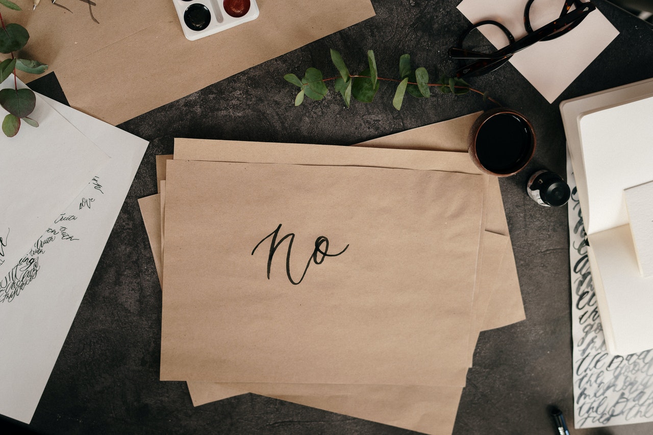 Desk with letters with a the word No written on a single page