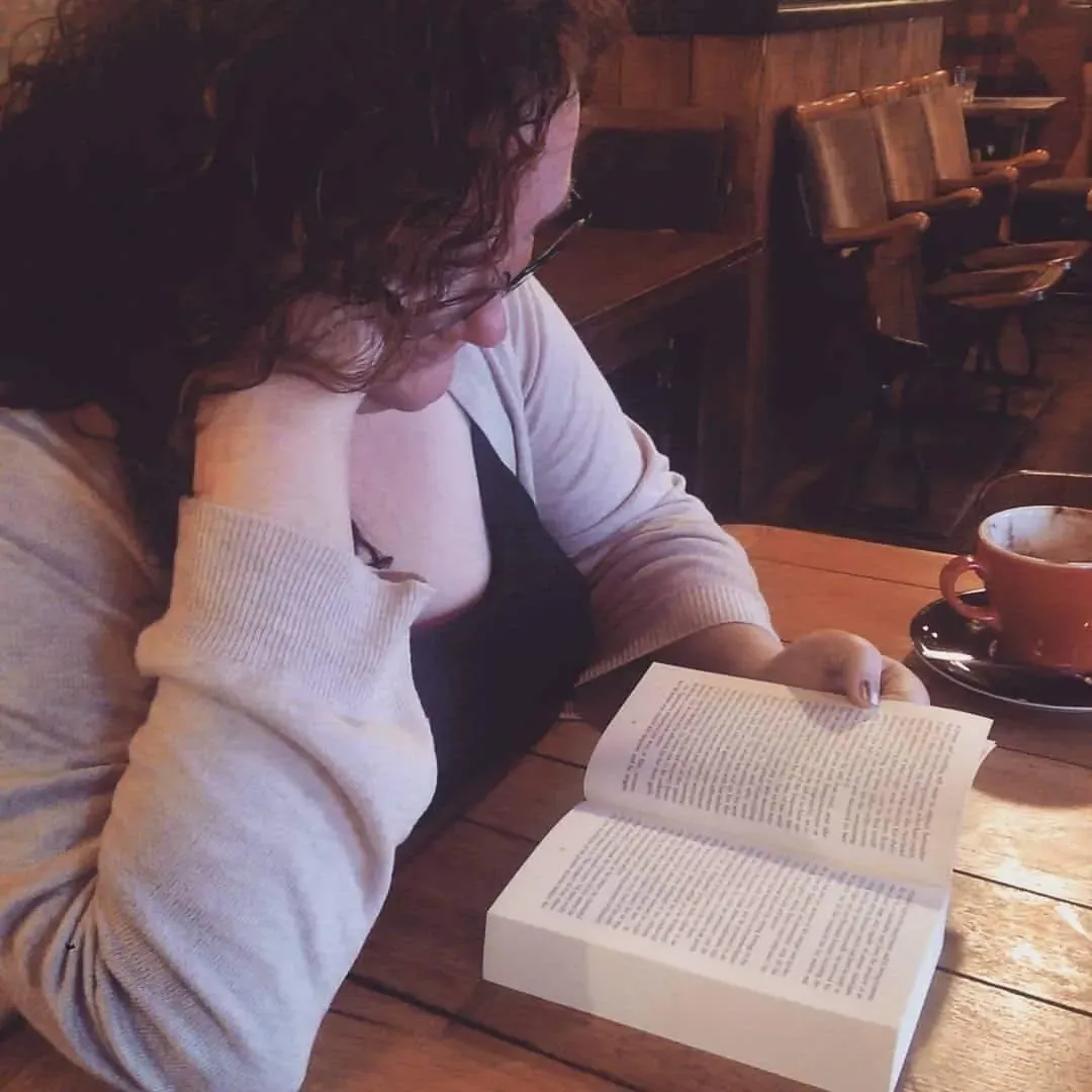 Sebrina reading a book in a coffee shop while drinking a nice cuppa.