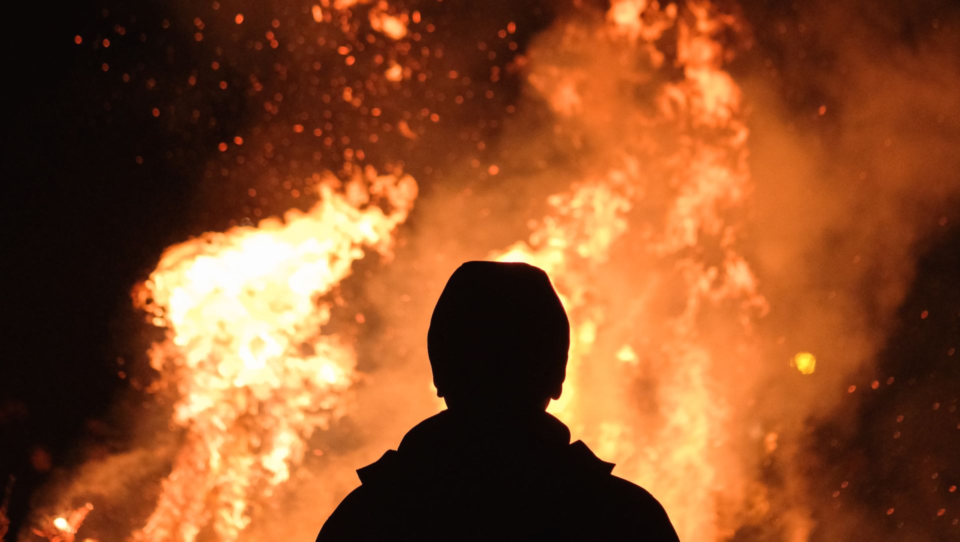 Person standing befoer a massive bonfire